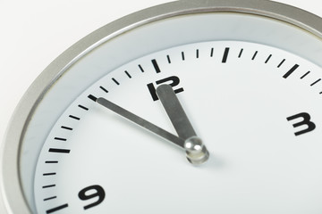Obraz na płótnie Canvas 5 minutes to 12 white with light metal minimalistic clock close-up on a light background