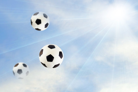 Soccer balls on a background of blue sky with clouds. The concept of sports business.