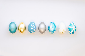Stylish Set of 7 blue, silver and gold Easter eggs isolated on white background Ester concept. Flat lay