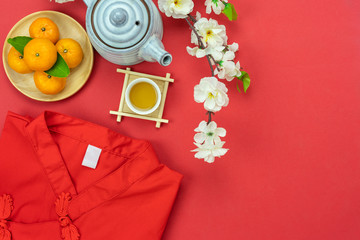 Chinese language mean rich or wealthy and happy.Accessories on Lunar New Year & Chinese New Year vacation concept background.Red T-shirt with cherry flower and cup of tea on modern red paper.