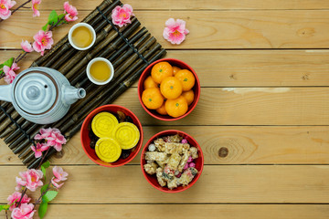 Table top view Lunar New Year & Chinese New Year vacation concept background.Flat lay orange in wood basket & pink cherry blossom with red pocket money & decorations on modern rustic brown backdrop