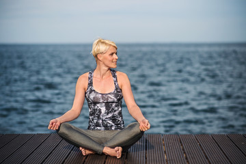 A portrait of young sportswoman doing yoga exercise on beach. Copy space.