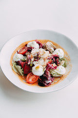  Cream cheese on a plate. Restaurant serving salad. Salad with almond shavings. Slicing fresh herbs and cherry tomatoes.