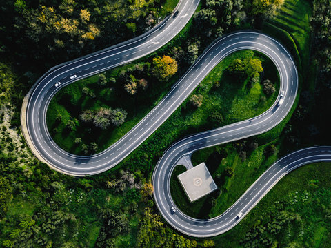 Aerial view of winding curved road with helicopter parking in Italy