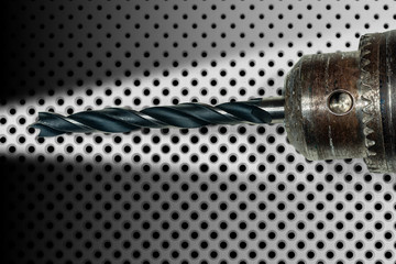 Extreme close-up of an electric drill with black tip on a white background with many black holes of...