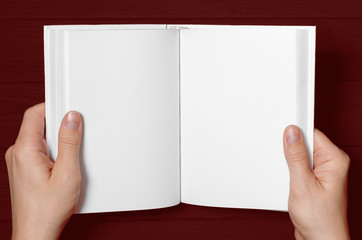 Men's hands hold a white book with clean pages