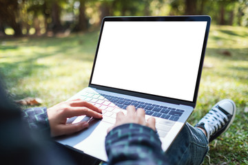 Mockup image of a woman using and typing on laptop with blank white screen , sitting in the...