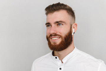 Obraz premium Image of cheerful handsome man smiling and using earpod