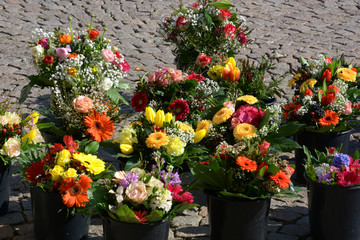 Fototapeta na wymiar mixed bunches of spring flowers in basket outdoors, bouquet of different flowers selling in a market on paving stones