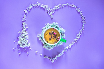 Flowering branch of white  lilac, lime cup of tea on purple background. Spring blossoming lilac top view, flat layout. Concept spring, summer, Mother's Day holidays, March 8, frame with copy space