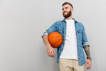 Image of bearded pleased man holding basketball and smiling