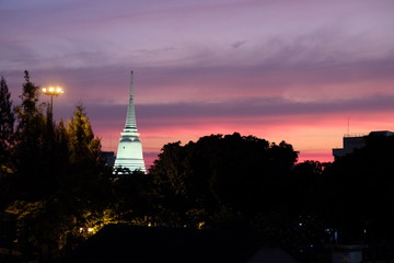 Obraz premium Beautiful sunset over the silhouettes of trees. Lighted spire of a Buddhist temple.
