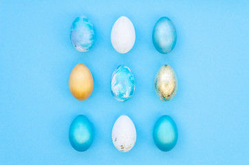 Stylish Set of blue, white and gold easter eggs isolated on light blue background. Easter concept, top view