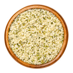 Hulled hemp seeds in wooden bowl. Raw and edible hempseeds. Small nuts of cannabis sativa. A mix of different hemp varieties. Closeup, from above, on white background, isolated macro food photo.