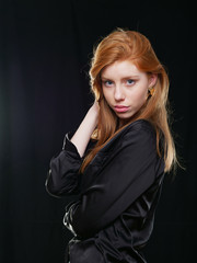 Fototapeta premium young girl with long red hair on a black background