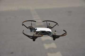 Mały dron na niskiej wysokości na tle parkingu przed sklepem. © W Korczewski