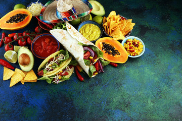 Fototapeta na wymiar Mexican food, including tacos, guacamole, nachos and pepper on rustic table
