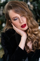 Portrait of a beautiful blonde girl with red lips and evening makeup, wavy hair wearing a black velvet jacket. Healthy, clean skin. Close-up. Advertising, commercial design.