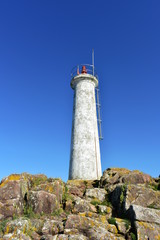 Fototapeta na wymiar Old white lighthouse on the rocks with blue sky. Muxia, Spain.