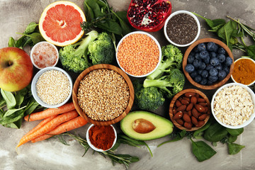Healthy food clean eating selection: fruit, vegetable, seeds, superfood, cereals, leaf vegetable on rustic background