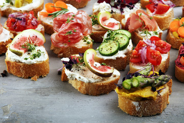 Assorted bruschetta with various toppings. Appetizing bruschetta or brie crostini. Variety of small sandwiches. Mix bruschetta on table