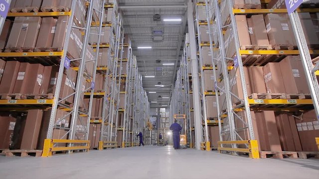 Forklift in a warehouse, a man in a large warehouse do the work