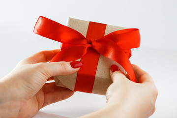 Gift with a red ribbon in hands on a white background