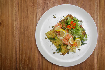 Smoked salmon with potato fritter, decorated with green salad and lemon slices. Exquisite dish. Creative restaurant meal concept.	