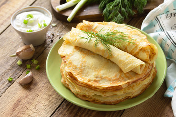 Potato pancakes, not sweet, served with garlic cream sauce on rustic wooden table. Copy space.
