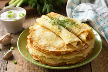 Potato pancakes, not sweet, served with garlic cream sauce on rustic wooden table.