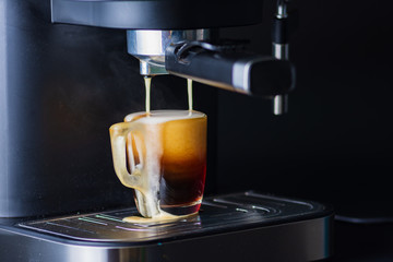 Espresso coffee is overflowing out of glass