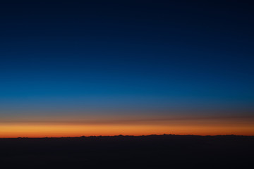 Beautiful view of sunset sky above clouds from airplane.