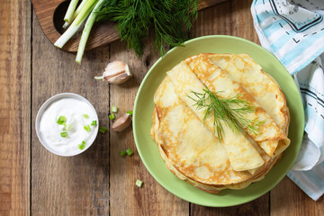 Potato pancakes, not sweet, served with garlic cream sauce on rustic wooden table. Top view flat lay background.