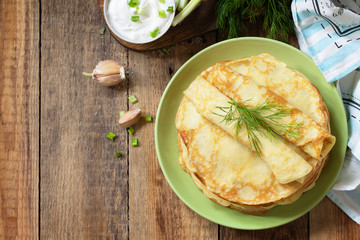 Potato pancakes, not sweet, served with garlic cream sauce on rustic wooden table. Top view flat lay background. Copy space.