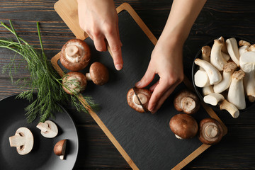 Woman cuts champignon on cutting board with mushrooms, top view © Atlas