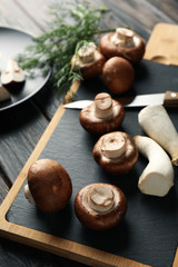 Obraz na płótnie Canvas Champignons, eringi, dill, knife and board on wooden table, close up