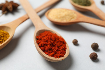 Spoons with different powder spices on grey background, close up