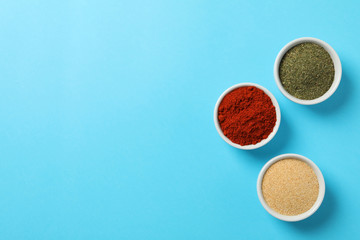 Bowls with red pepper, garlic and dill powder on blue background, top view