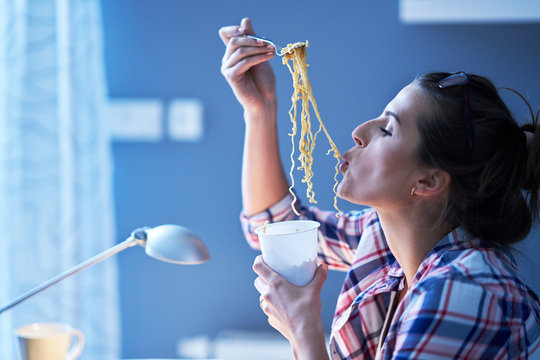 Hungry Student Eating Noodle While Learning At Home