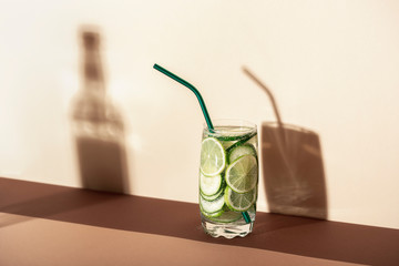 Glass of lemonade with cucumber and lime in harsh light. Detox drink