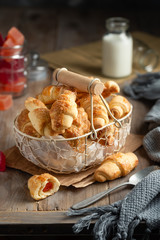Homemade bagel cookies with marmalade inside. Sweet croissant cookies in a basket on a wooden background. Selective focus