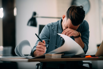 Tired businessman in office. Young architect overworked. 