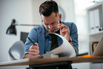 Tired businessman in office. Young architect overworked. 