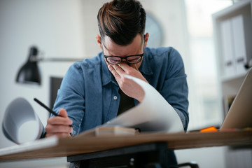 Tired businessman in office. Young architect overworked. 