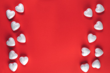 Minimalistic valentine's day or wedding composition with frame of many white hearts on a red paper background, flat lay, top view, copy space