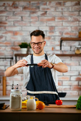 Young man in kitchen taking photo of food. Handsome man in kitchen. 