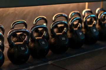 For you to choose. Stylish kettlebells weights made of black leather and iron lying in a row on the...