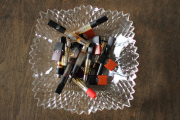Closeup of assorted vape pods and cartridges in a glass ashtray.