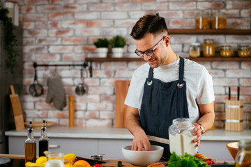 Fototapeta na wymiar Young chef in modern kitchen. Young man making dough. 