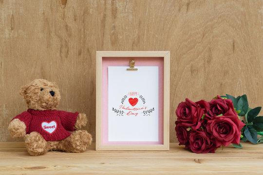 Mockup Picture frame and cute bear with Bouquet of red roses on rusty wood. Valentines Day Background concept with copy space. Mock up with photo frame for your picture or text